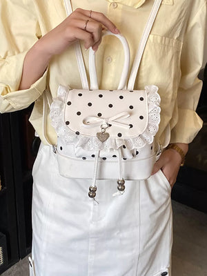 Charming white polka dot lace mini backpack with bow and heart charm detail.