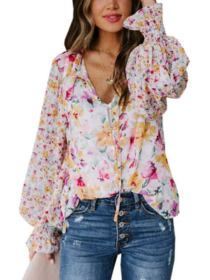 Vibrant floral print blouse with tie detail, button front, and smocked cuffs.