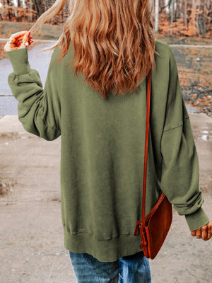 Moss green sweatshirt with balloon sleeves and side slits, styled with a crossbody bag.