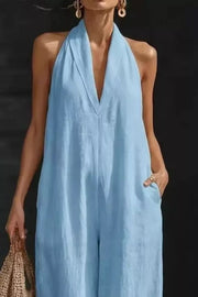 Light blue halter neck jumpsuit with pockets and a deep V-neck.