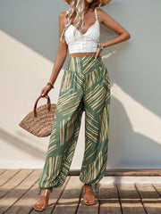 Moss green palazzo trousers with abstract print, smocked waistline, and ankle ties.