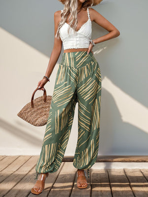Moss green palazzo trousers with abstract print, smocked waistline, and ankle ties.