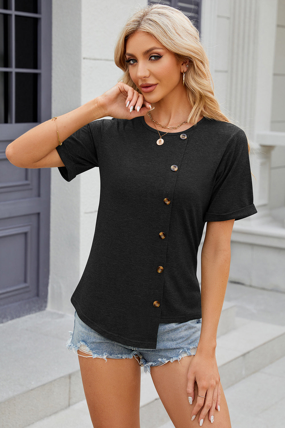 Black asymmetric button-up tee with short sleeves and a rounded neckline.