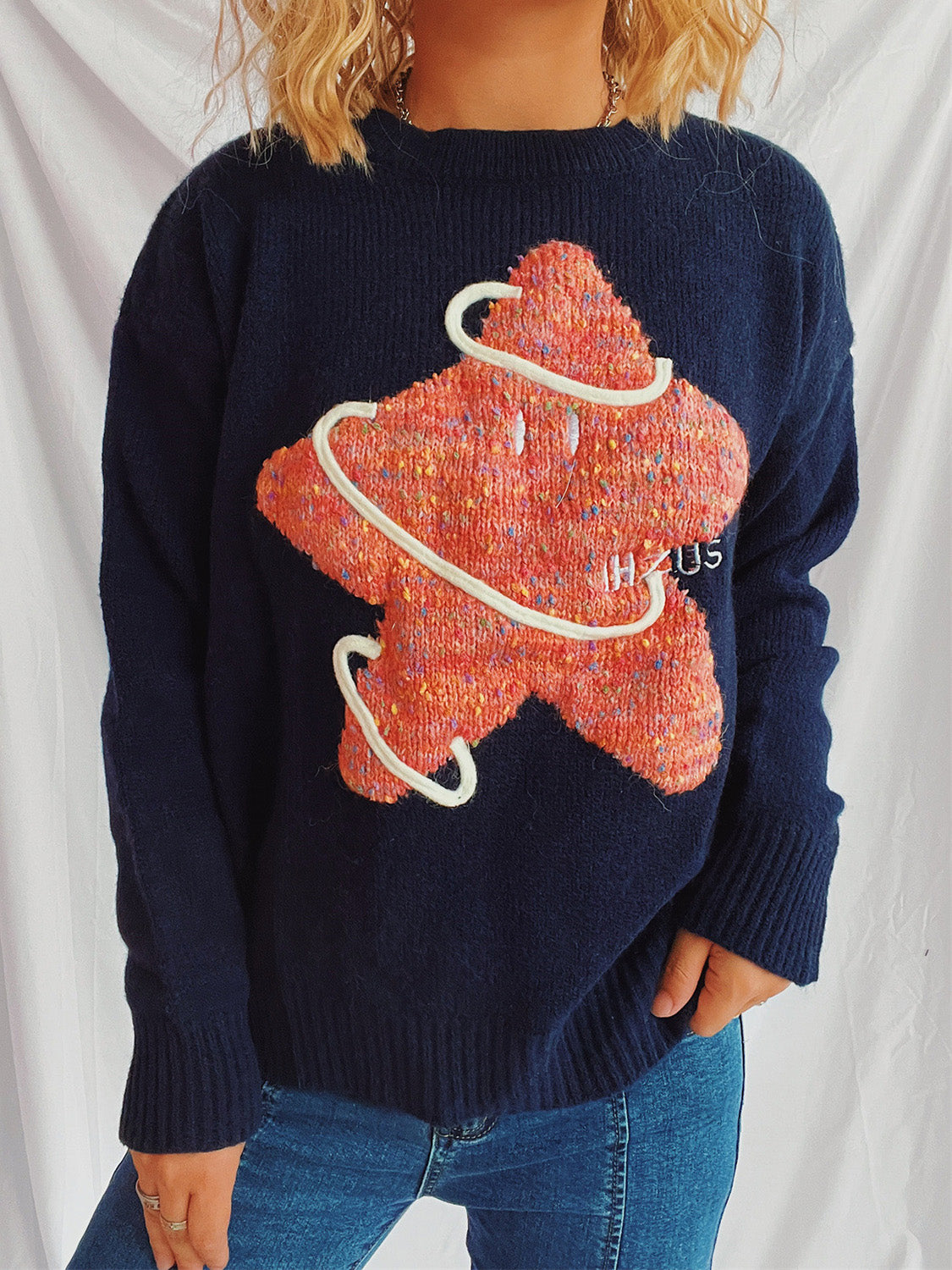 Navy knit jumper with embroidered starburst detail and white piping, crewneck, long sleeves.