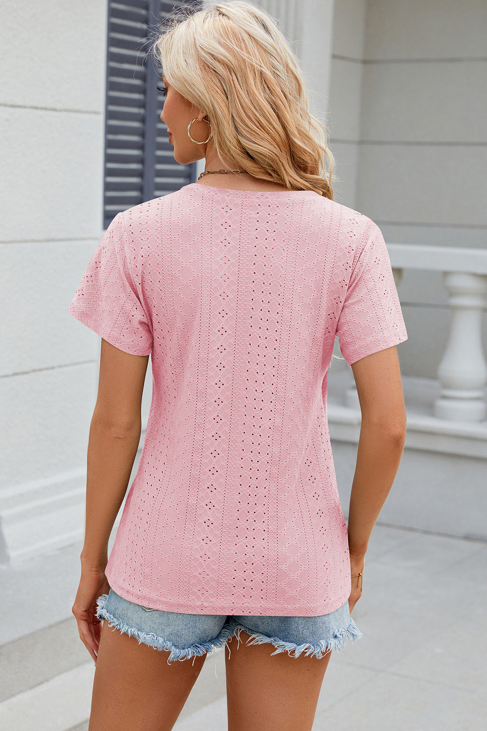 Blush pink eyelet v-neck top with short sleeves and a casual fit.