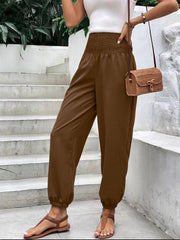 Brown relaxed-fit trousers with smocked waistline and elastic cuffs.