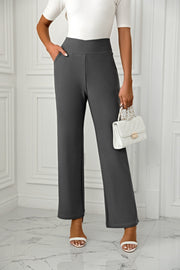 Dark gray wide-leg trousers with a sculpted waist and pockets, styled with white heels.