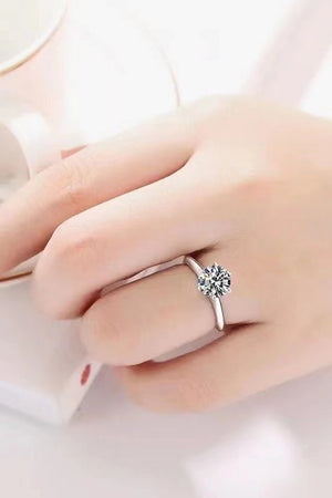 Silver ring with a brilliant cut moissanite solitaire stone on a hand.