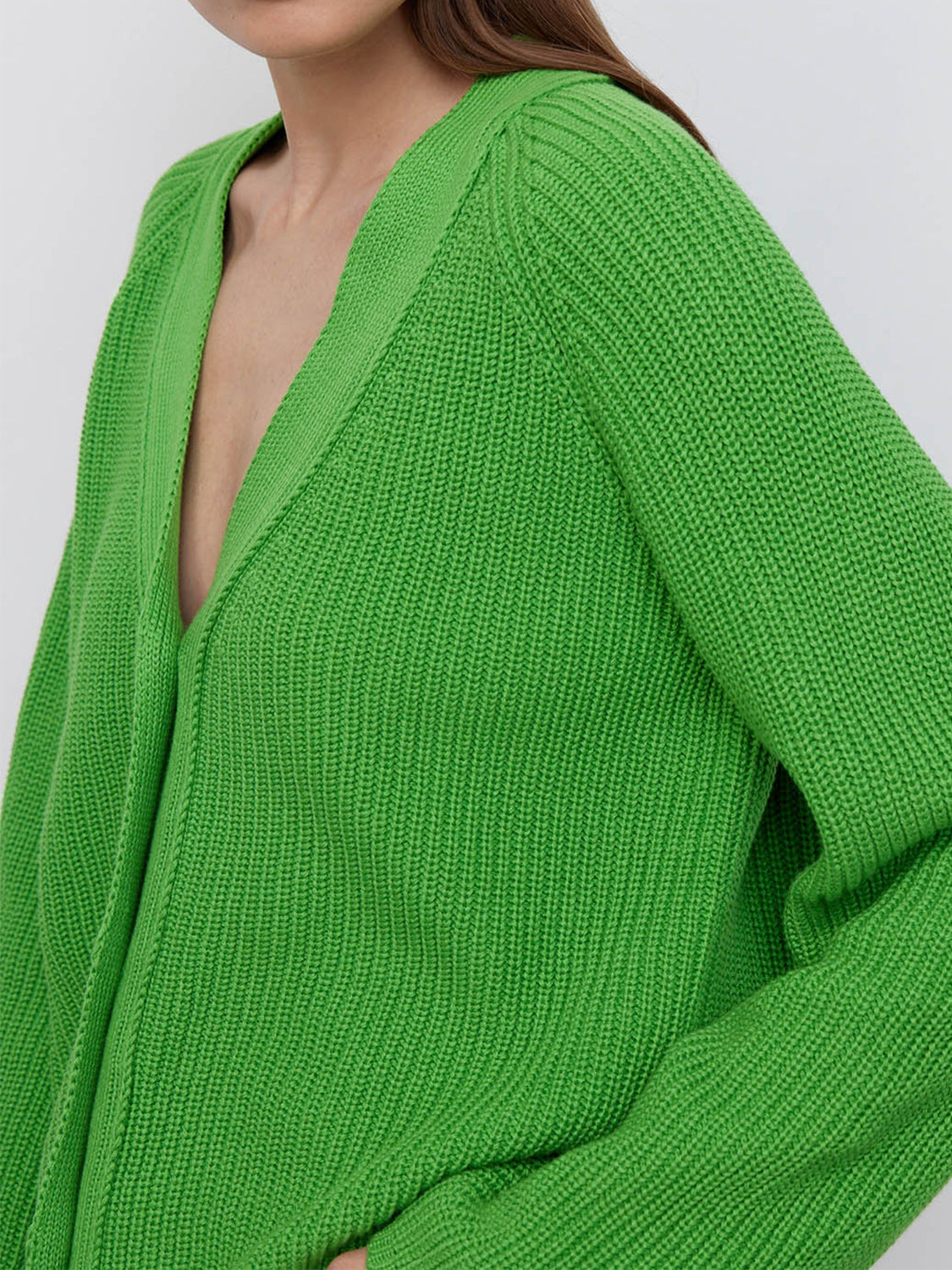 Green ribbed knit cardigan with deep V-neck and raglan sleeves.