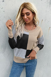 Geometric panel knit sweater in black, tan, gray, and white with crew neck and long sleeves.