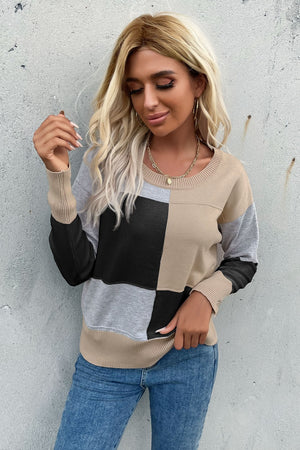 Geometric panel knit sweater in black, tan, gray, and white with crew neck and long sleeves.