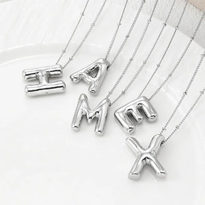 Sculpted initial pendant necklaces in silver with beaded chains, featuring bubble letters.