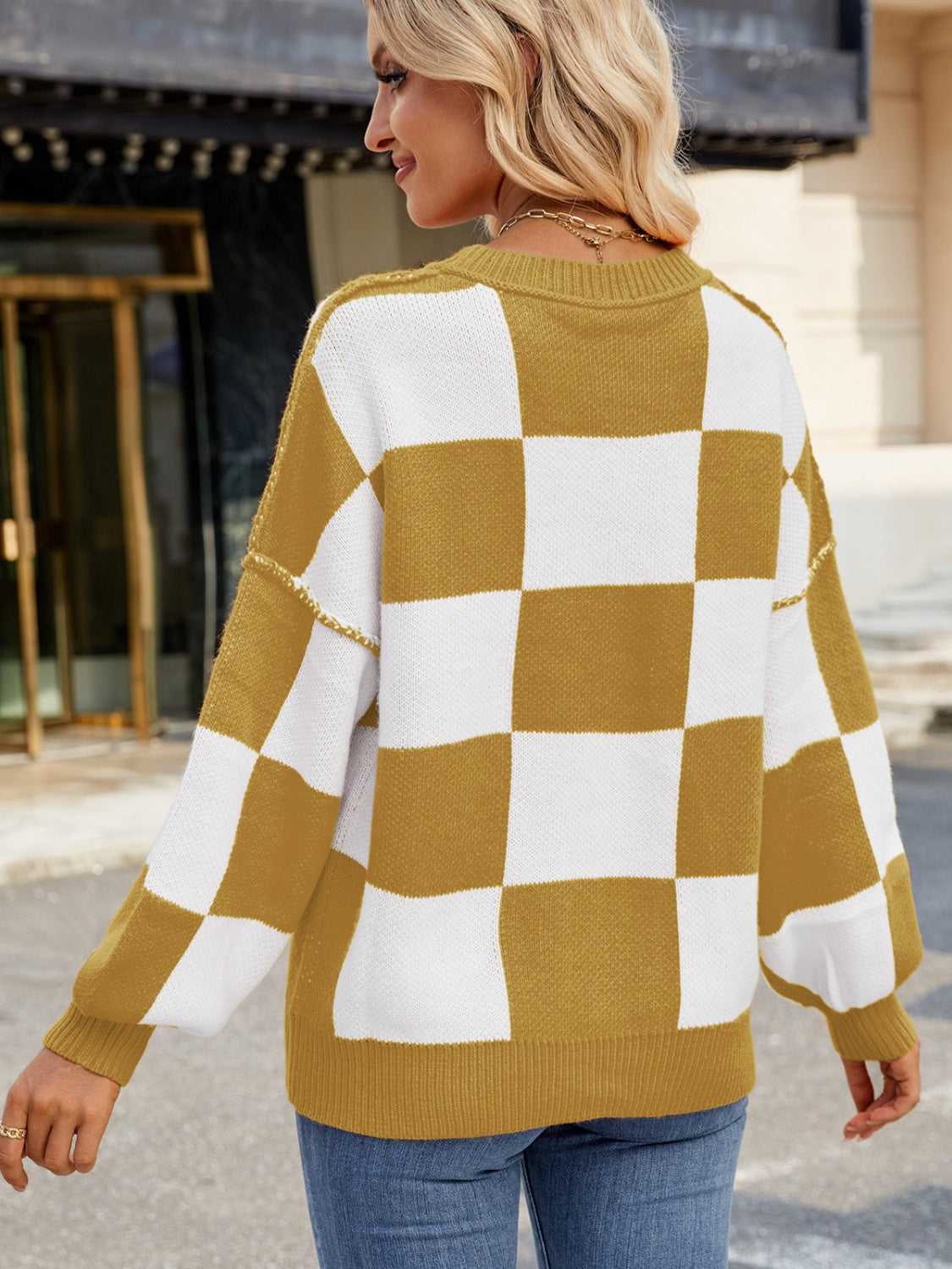 Checkerboard knit sweater in mustard and white with balloon sleeves.