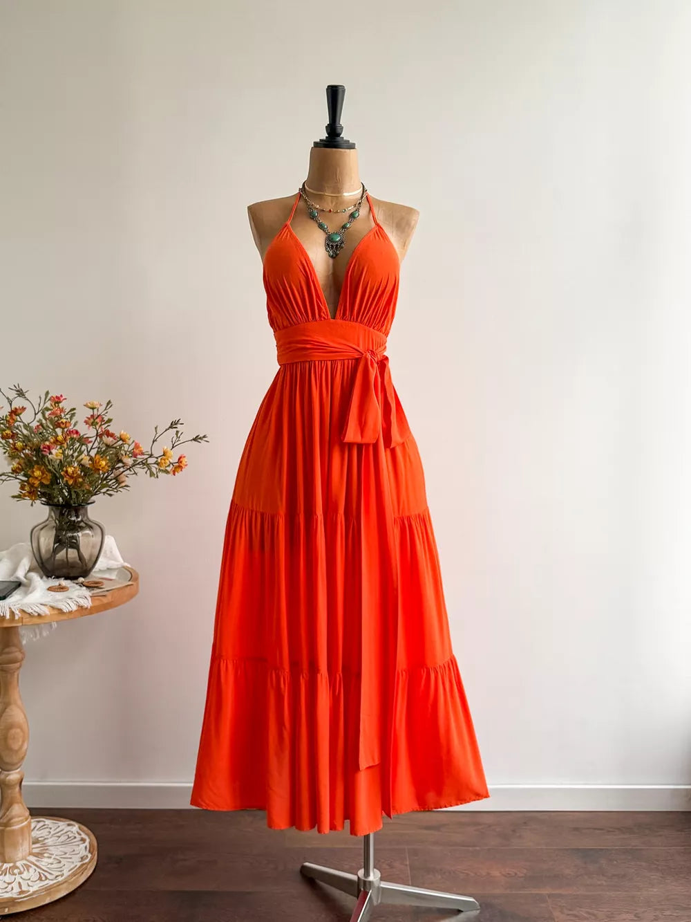 Orange tiered maxi dress with plunging V-neck, cinched waist, and halter straps.