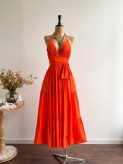 Orange tiered maxi dress with plunging V-neck, cinched waist, and halter straps.