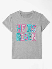 Gray crewneck t-shirt with sequin "He Is Risen" graphic in aqua and pink.
