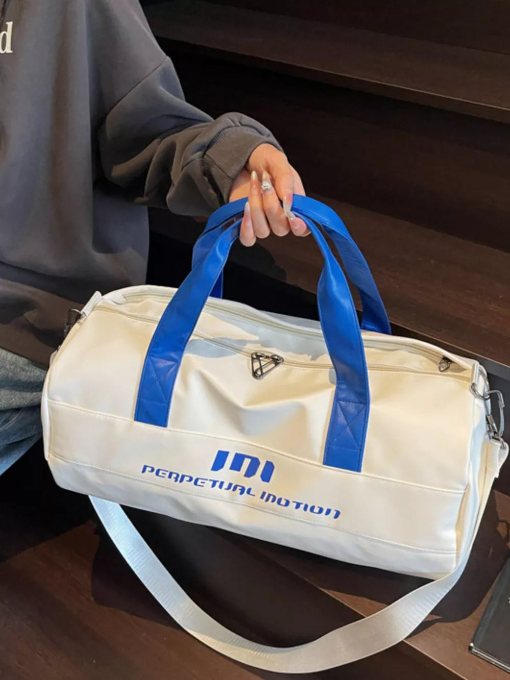 Off-white pu leather sporty duffel bag with blue handles and bold graphic text.