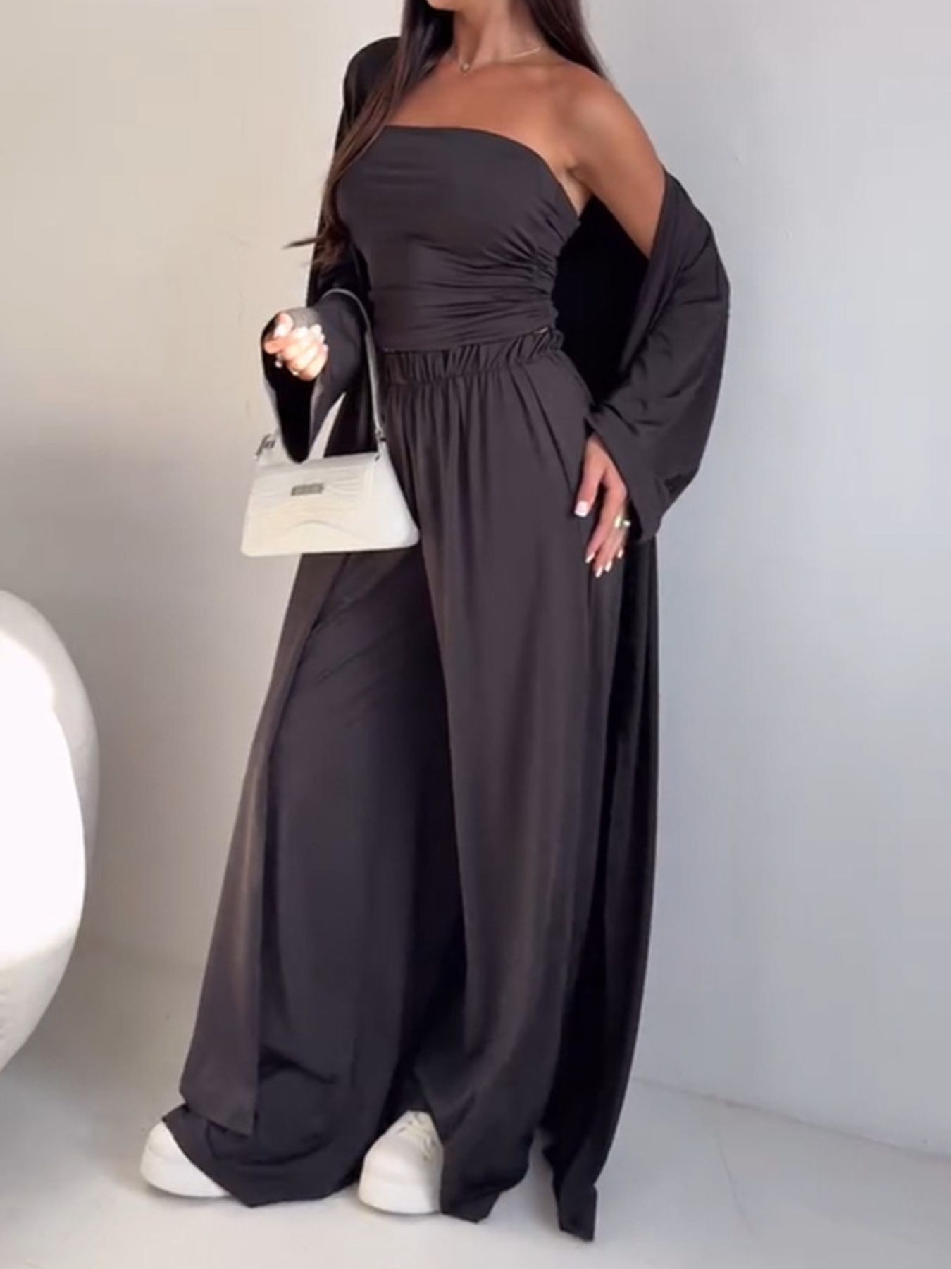 Dark brown three-piece outfit set with ruched strapless top, wide-leg pants, and long cardigan.