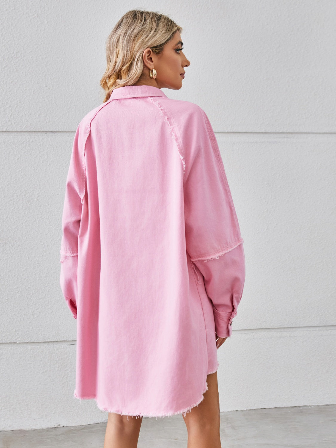 Pink denim shirt dress with raw hem and button cuffs, shown from the back.