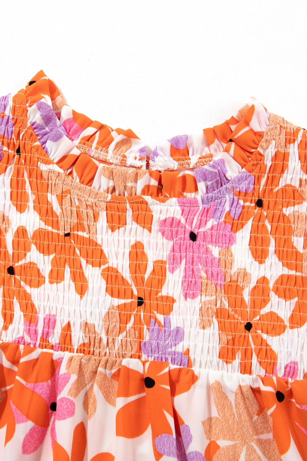 Multicolor floral smocked bodice blouse with ruffled neckline and flutter sleeves.
