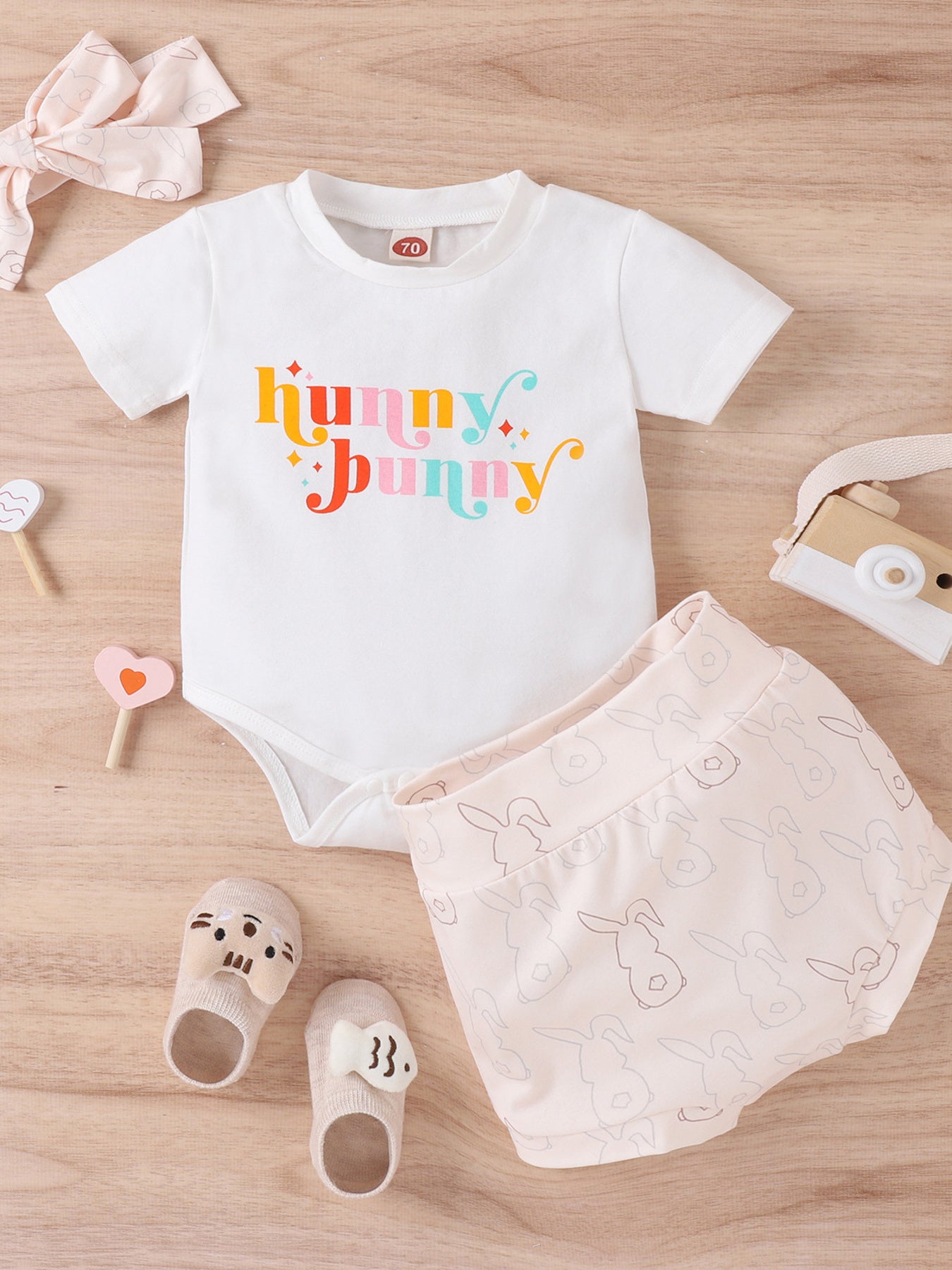 White baby bodysuit with colorful "hunny bunny" graphic and pink bunny print shorts.