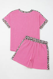 Pink ribbed pajama set with crew neck top and shorts featuring leopard trim details.