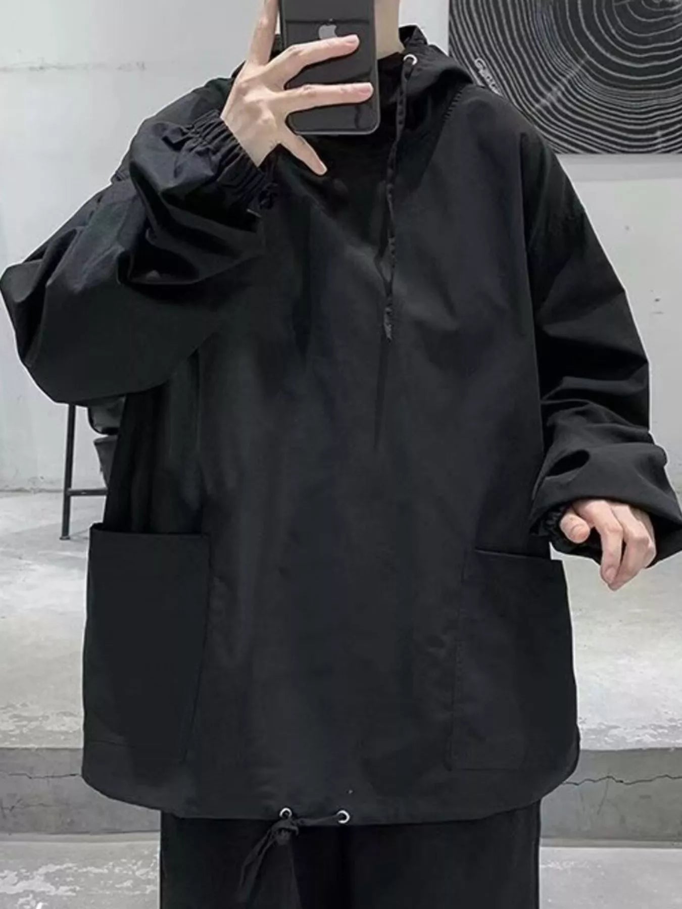 Black oversized drawstring hoodie with large front pockets and cinched cuffs.