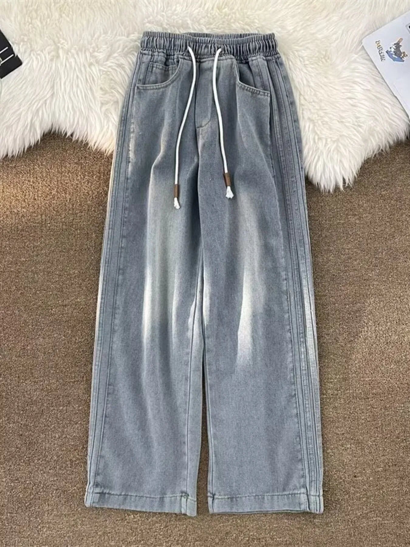 Men's light blue wide-leg jeans with drawstring waist and distressed details.