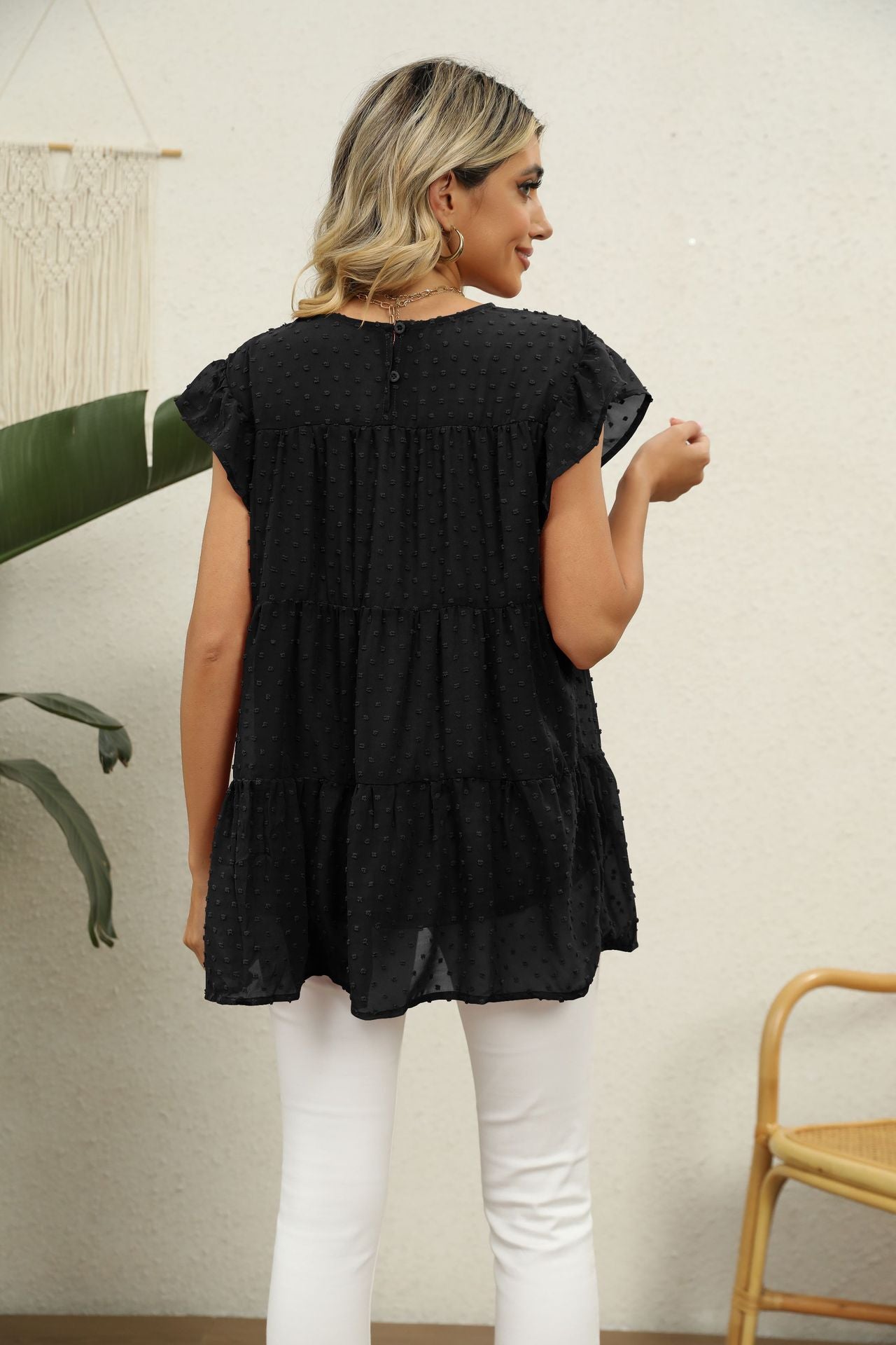 Black Swiss dot tiered blouse with flutter sleeves and round neckline.