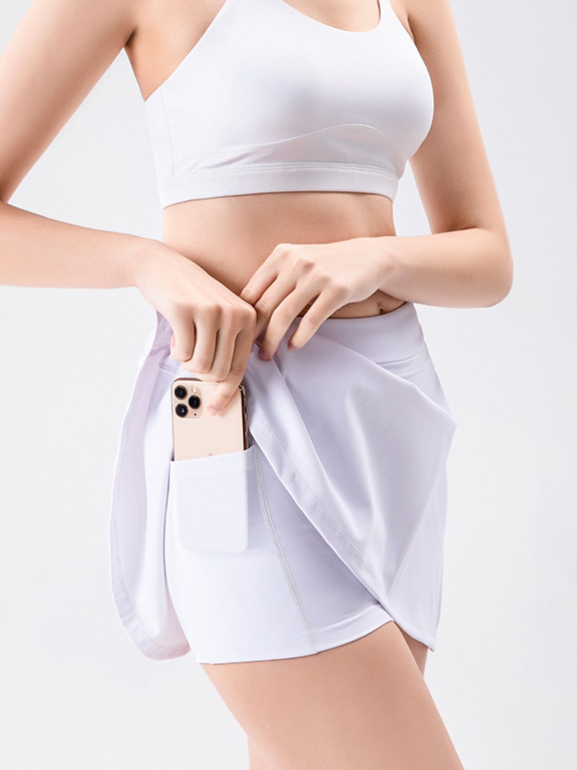 White skort with wrap detail and side tie, showing phone pocket.
