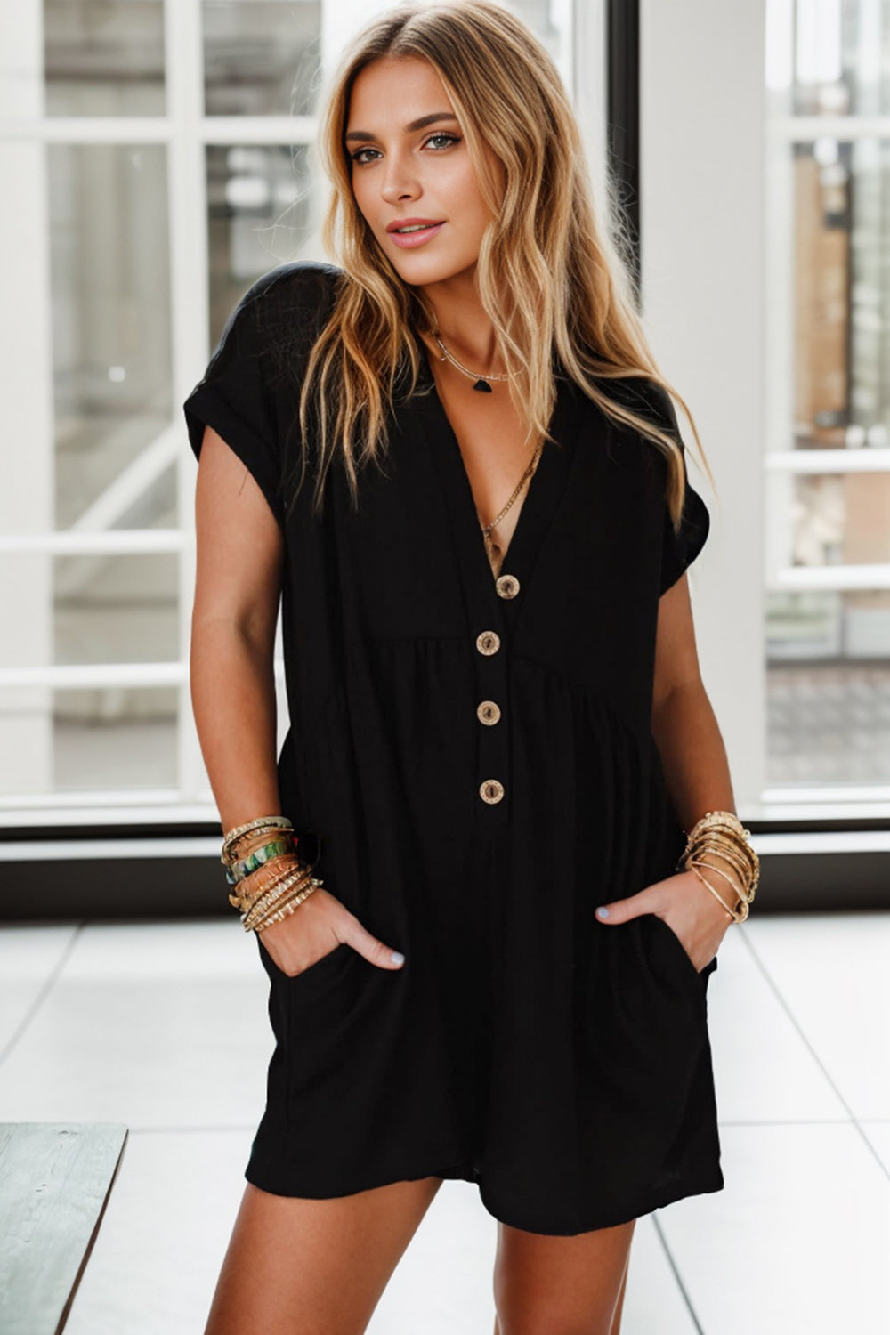 Black button-down empire waist romper with short sleeves and V-neckline.