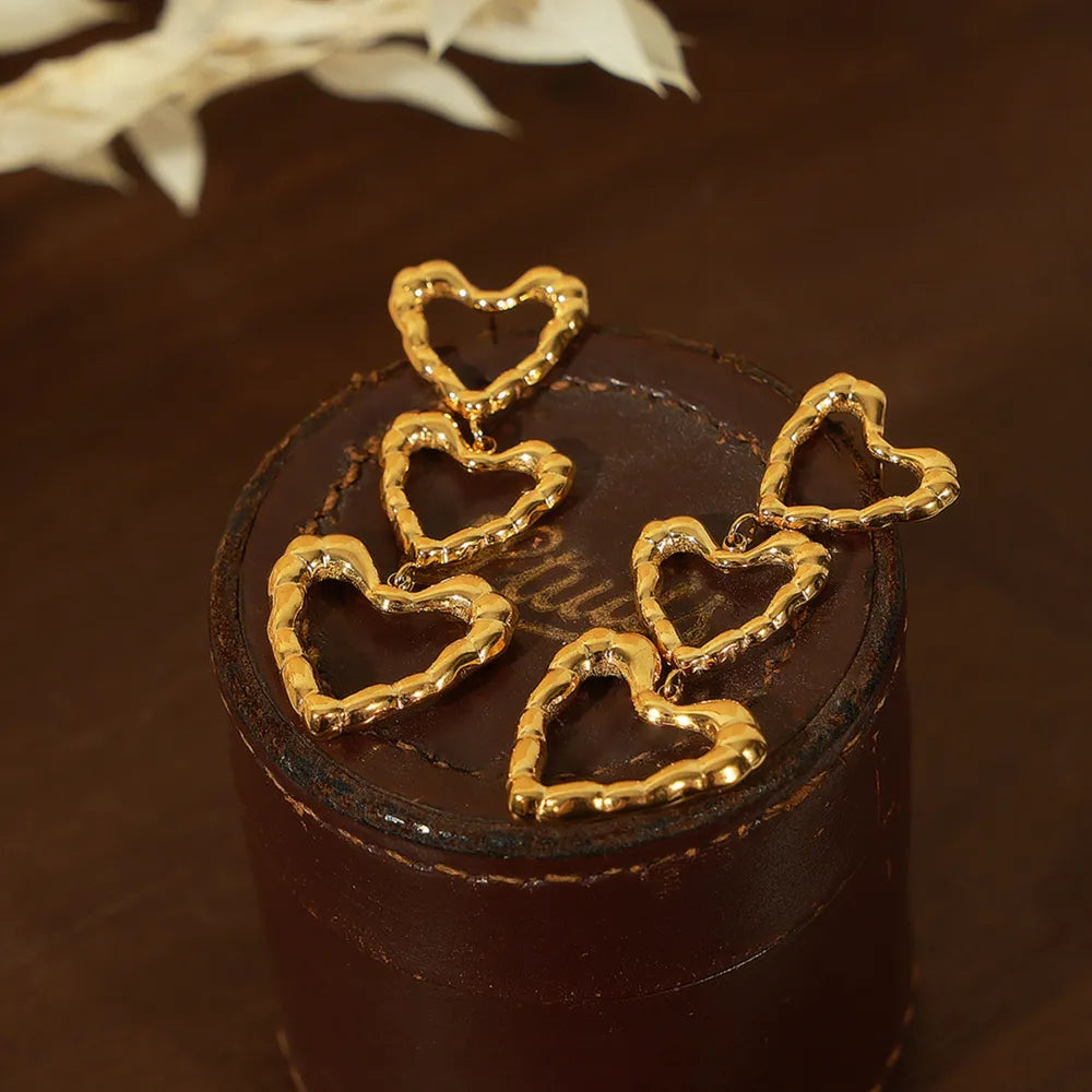 Gold triple heart drop earrings with textured edges