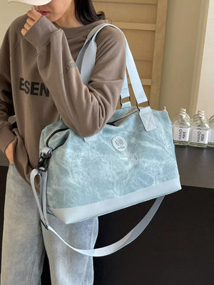 Distressed blue duffle bag with adjustable strap and light blue trim