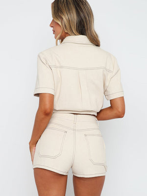 Cream utility set with contrast stitching, featuring a buttoned short sleeve shirt and high-waisted shorts.