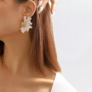 White textured flower stud earrings with gold center detail.