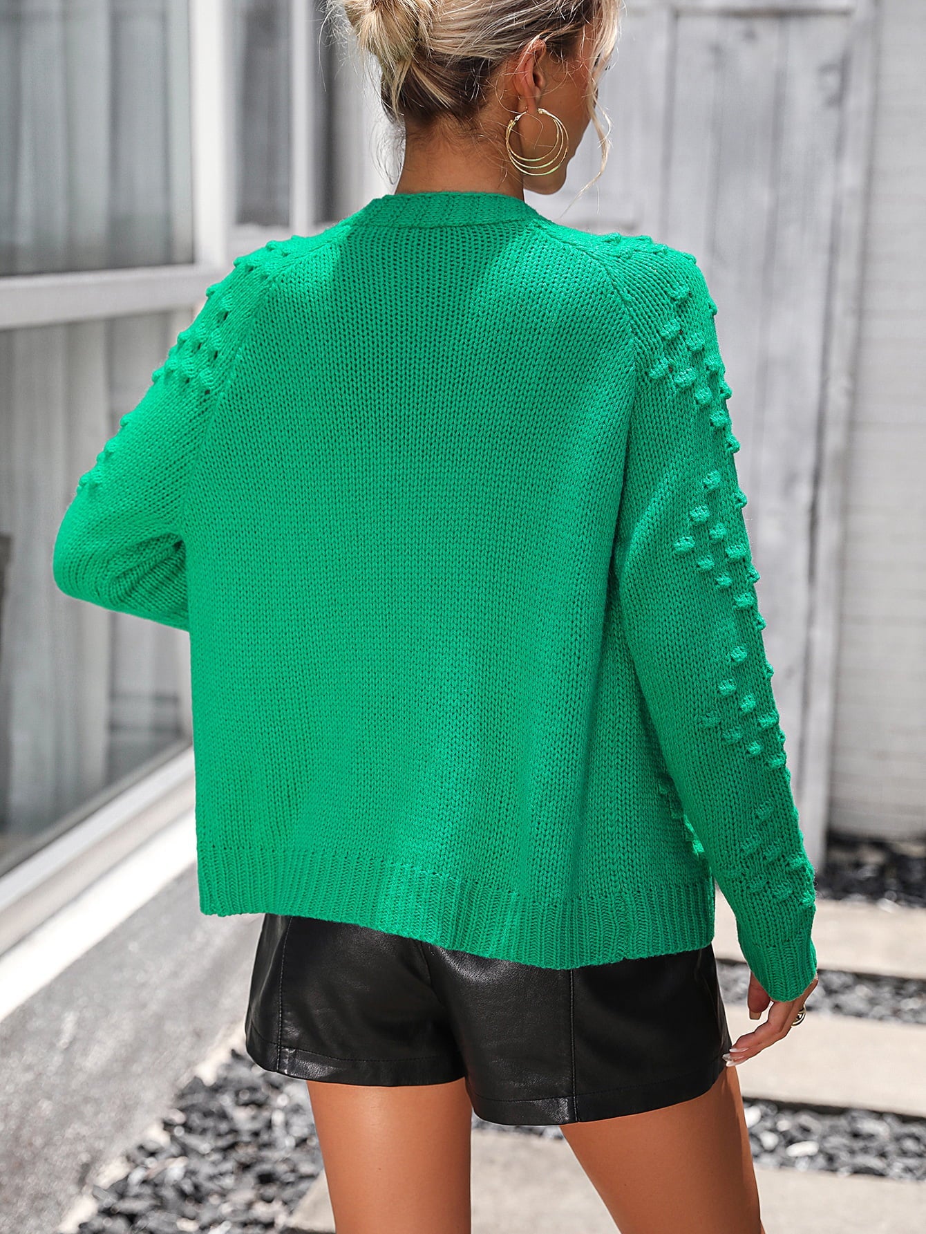 Green acrylic cardigan with textured sleeve details and ribbed hem.