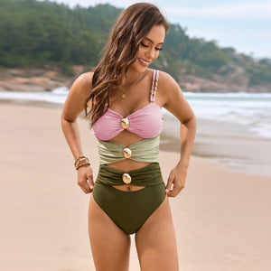 Colorblock one-piece swimsuit in pink, sage green, and olive with gold hardware details.