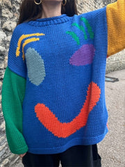 Blue knit sweater with abstract graphic pattern and colorblock sleeves.