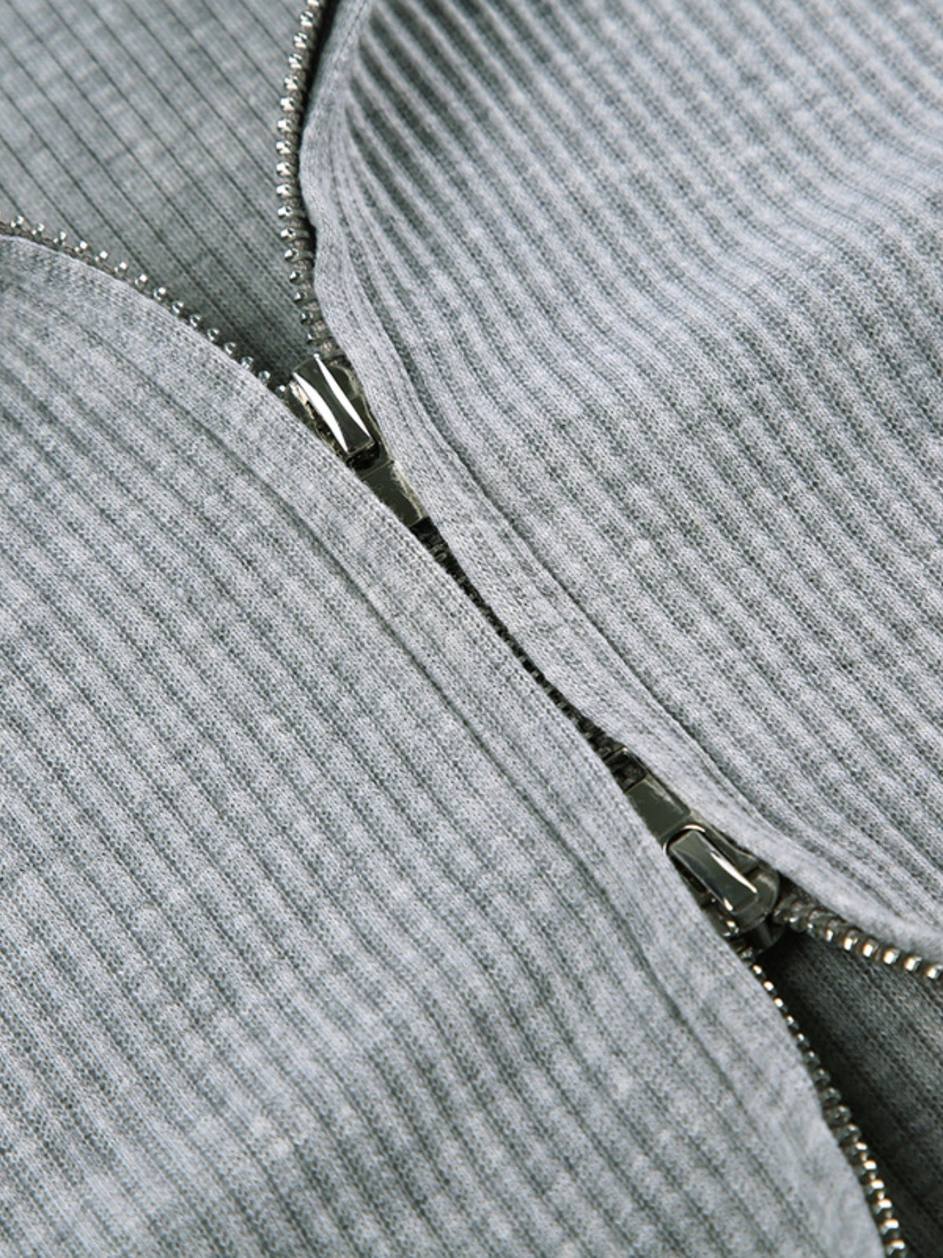 Grey ribbed knit hoodie detail with a silver zipper closure