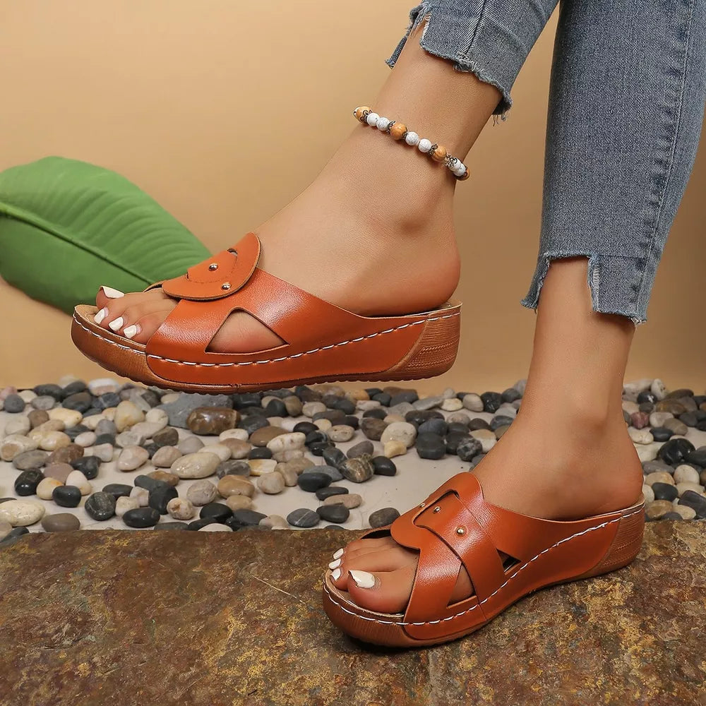 Orange embellished open-toe wedge sandals with decorative straps and white stitching.
