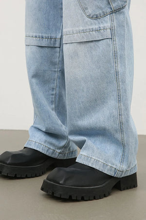 Baggy light wash denim cargo pants with utility pockets and a wide leg.