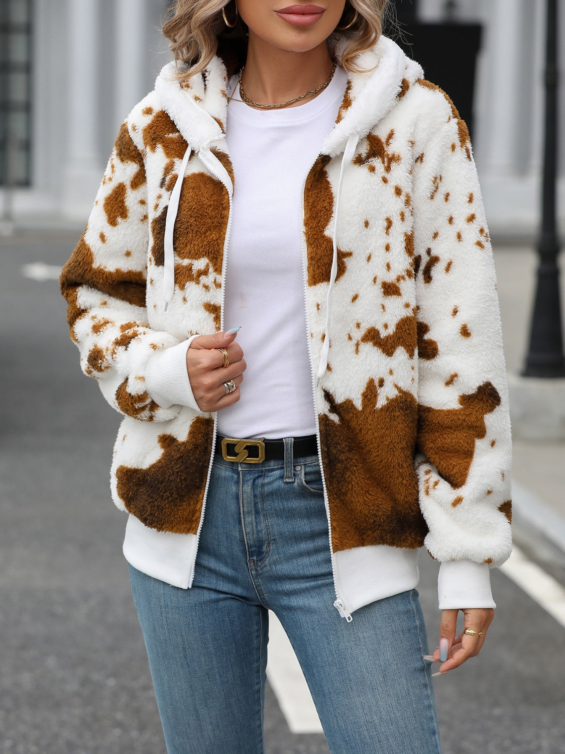Cowhide print sherpa zip-up hoodie with white trim and drawstring hood.