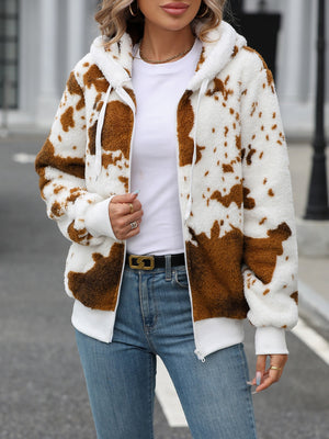 Cowhide print sherpa zip-up hoodie with white trim and drawstring hood.