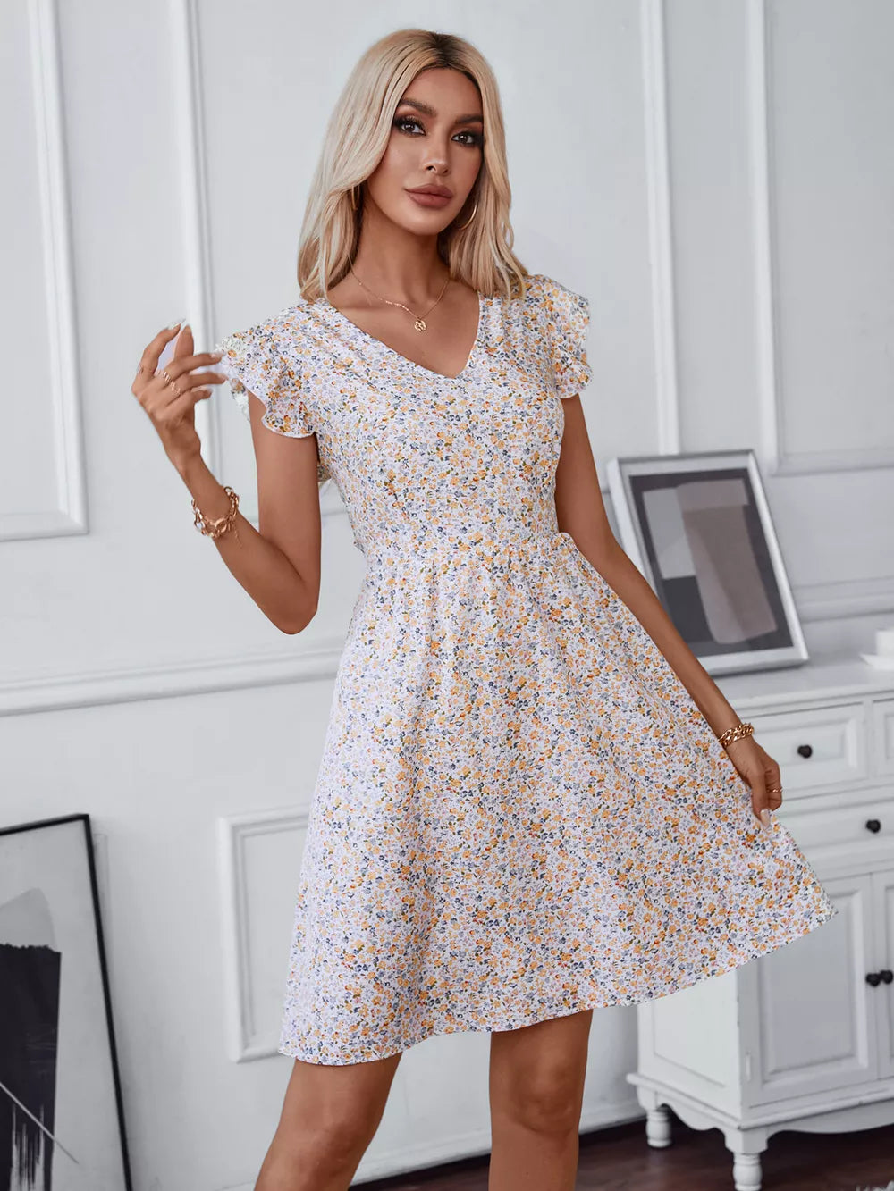 Ditsy floral mini dress with V-neck, ruffled short sleeves, and a flared skirt.