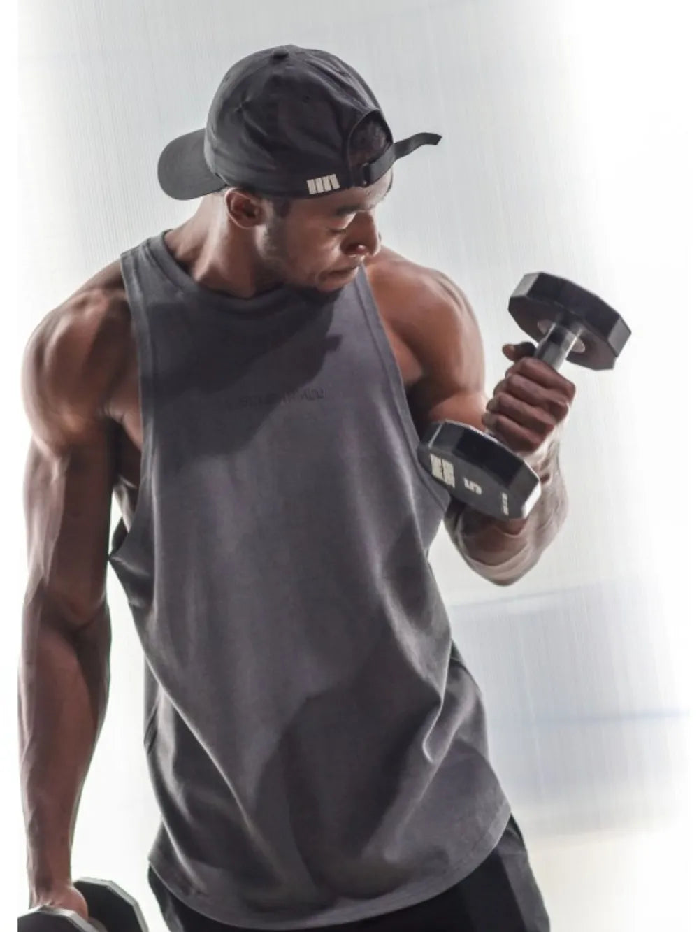 Gray muscle tank top with a washed cotton blend look, worn by a man lifting weights.