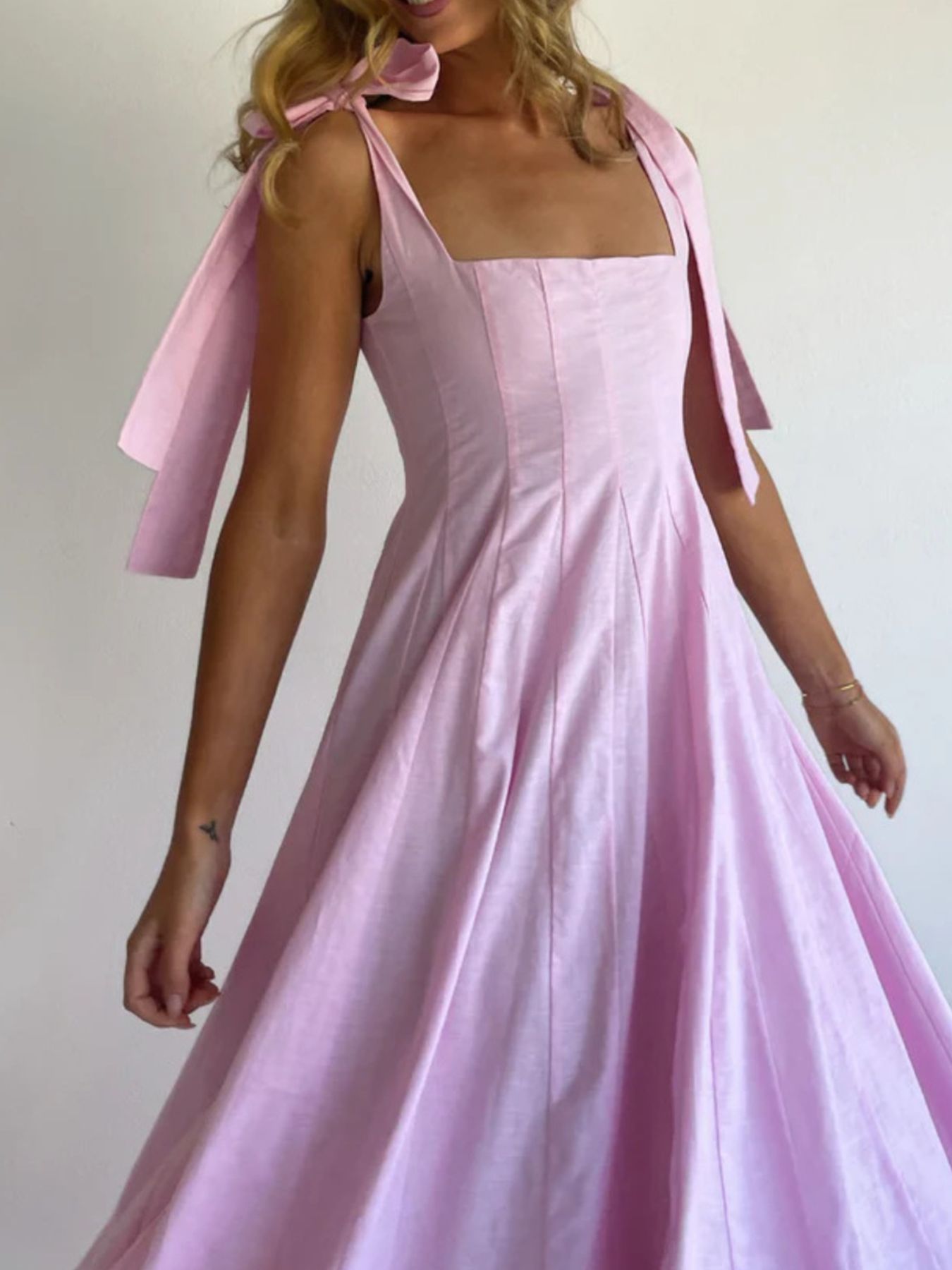 Pink maxi dress with square neckline and bow-tie shoulder straps.