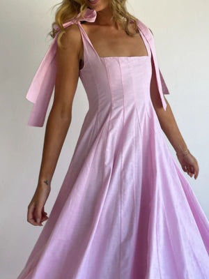 Pink maxi dress with square neckline and bow-tie shoulder straps.