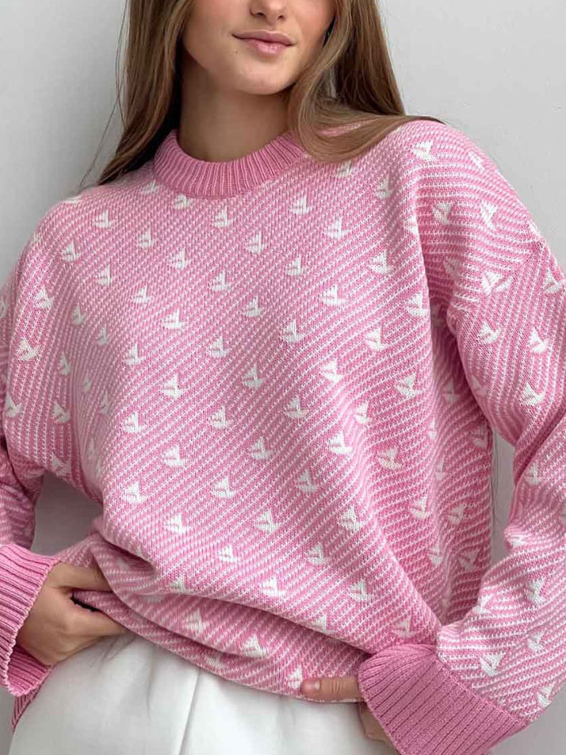 Blush pink knit sweater with all-over white sailboat jacquard pattern and ribbed crewneck.