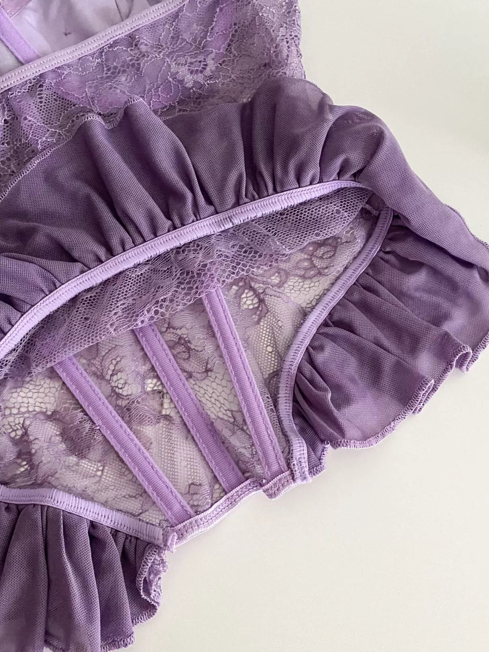 Purple lace bustier top with ruffled mesh trim and boning detail.