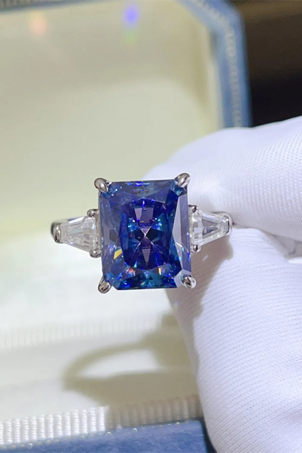 Radiant cut royal blue sapphire and moissanite ring with three stones.
